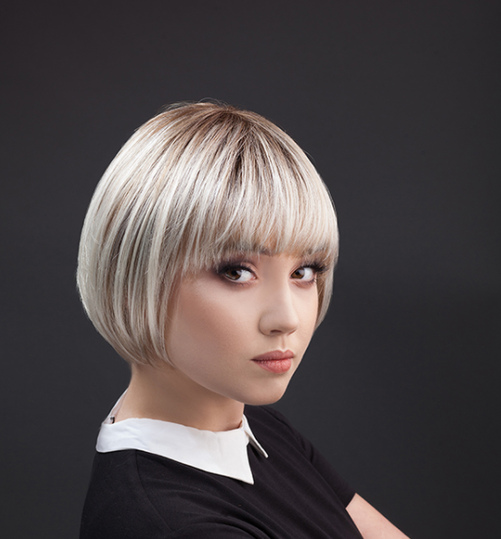 Młoda kobieta z krótką, blondynką fryzurą, patrząca na lewo, ubrana w czarną bluzkę z b whiteową kołnierzykiem.