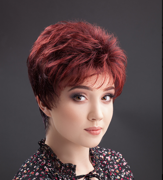 Kobieta z krótkimi, czerwonobrązowymi włosami, delikatnym makijażem i uśmiechem, ubrana w czarną bluzkę z kwiatowym wz