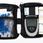 Przenośny zestaw medyczny z glukometrem, strzykawkami, insuliną i akcesoriami do pomiaru poziomu cukru we krwi.