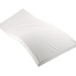 Materac z białej pianki na płaskiej powierzchni, bez pościeli.