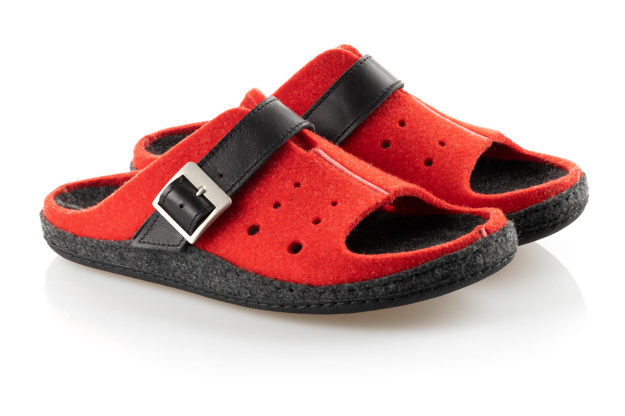 Czerwone kapcie z czarnym paskiem i metalową klamrą, wykonane z miękkiego materiału, na czarnej podeszwie.
