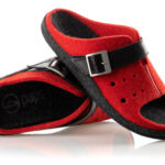 Czerwone i czarne kapcie z regulowanym paskiem, wykonane z filcu, na białym tle.