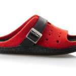 Czerwone kapcie z czarną podeszwą i czarnym paskiem z metalową klamrą, wykonane z filcu.