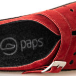 Czerwone buty z czarnym wkładką, logo paps i metalowym zapięciem na pasek.