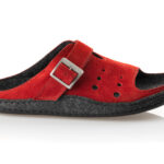 Czerwone kapcie z czarną wyściółką, pasek z metalową klamrą i perforacjami na bokach.