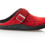 Czerwony, miękki pantofel z czarną podeszwą i metalową klamrą, z perforacjami na wierzchu.