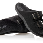 Czarne kapcie z dwoma paskami na rzepy i metalowymi klamrami, wykonane z miękkiego materiału, na białym tle.
