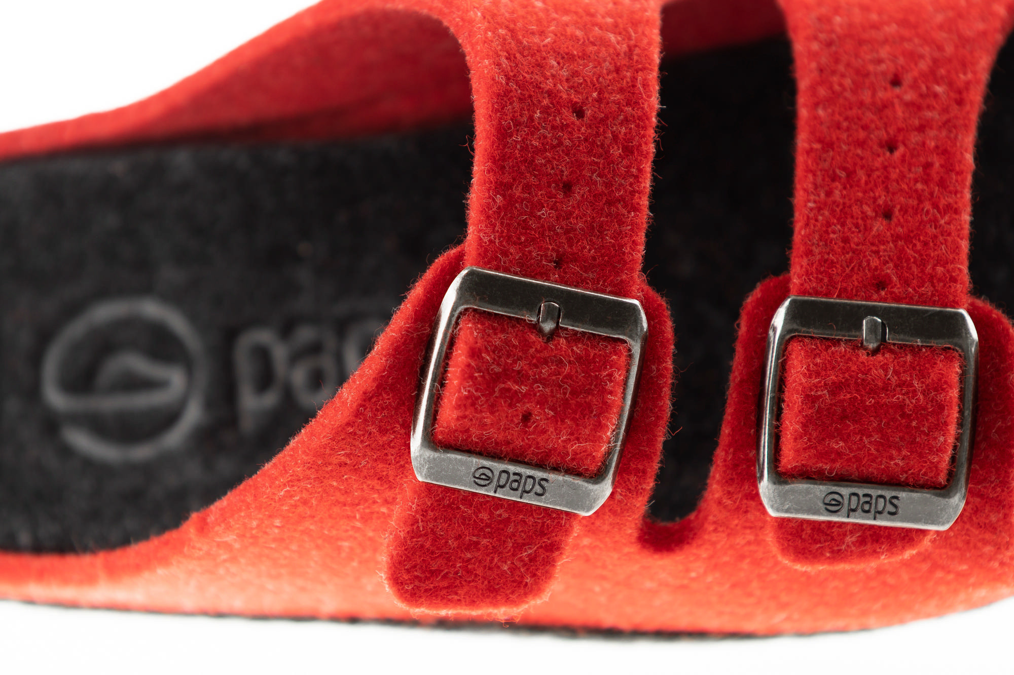Czerwone paski z metalowymi klamrami na czarnym, miękkim materiale, z widocznym logo pade.