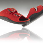 Czerwone kapcie profilaktyczne z czarną podeszwą i dwoma regulowanymi paskami na rzepy.