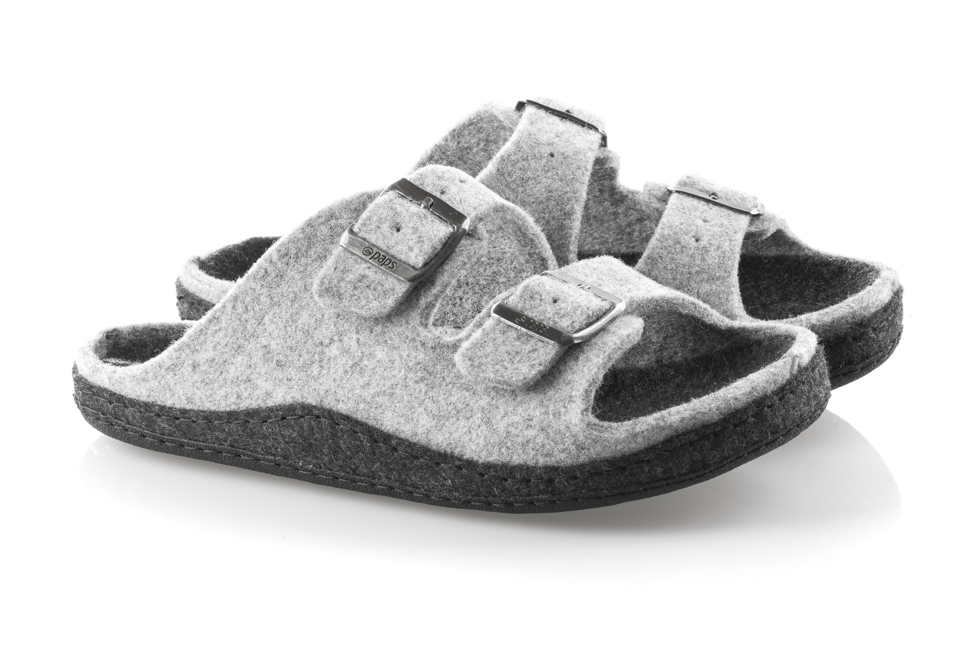 Szare kapcie z dwoma metalowymi klamrami i miękkim, filcowym materiałem, na czarnej podeszwie, ustawione na białym tle.