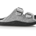 Szara kapcie z dwoma regulowanymi paskami na rzepy, wykonane z miękkiego materiału, na czarnej podeszwie.