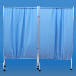 Przenośna zasłona w kolorze niebieskim na kółkach, służąca do tworzenia prywatnych przestrzeni.