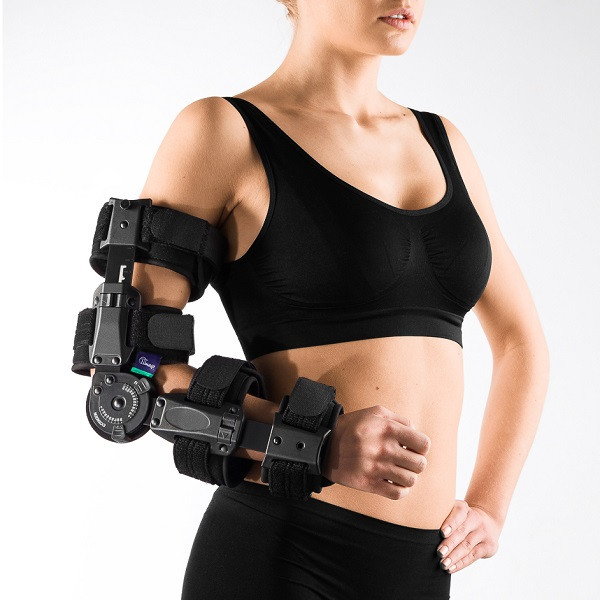 Kobieta w sportowym stroju, z protezą ramienia wyposażoną w mechaniczne elementy i paski mocujące.