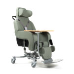 Fotel rehabilitacyjny z podnóżkiem, regulowanym zagłówkiem i podłokietnikami, na kółkach, w kolorze zielonym.