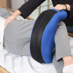 Osoba leżąca na łóżku, otrzymująca masaż pleców z użyciem poduszki masującej.