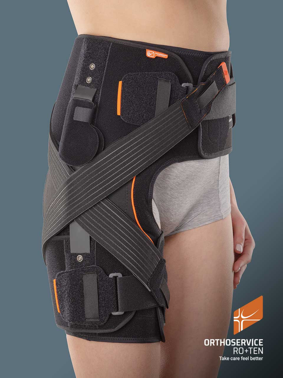 Pas biodrowy ortopedyczny z czarnymi pasami, elementami mocującymi i kieszeniami, na modelu w szarych spodniach.