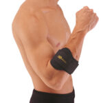 Mężczyzna z opaską na nadgarstku, wykonującym ćwiczenie siłowe, widoczny od ramion do pasa, na jasnym tle.