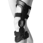 Kobieta nosi stabilizator kolana z paskami i zapięciami, oznaczony logo ortopedico.