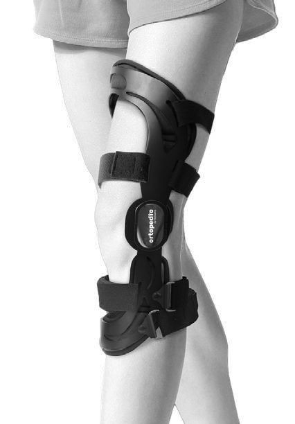 Kobieta nosi stabilizator kolana z paskami i zapięciami, oznaczony logo ortopedico.