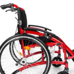 Czerwony wózek inwalidzki z czarnym siedziskiem i podłokietnikami, widok z boku na koła i ramę.