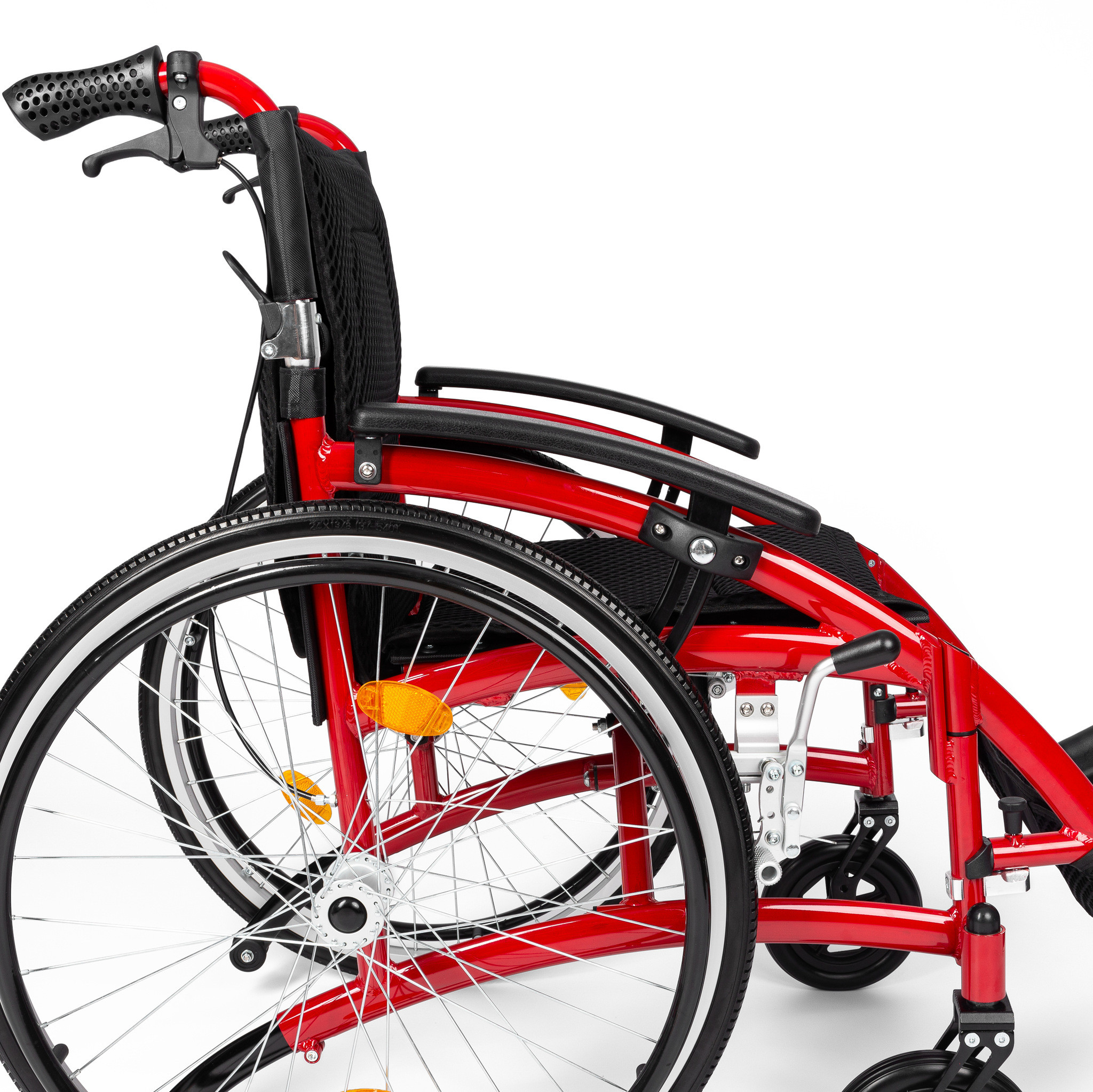 Czerwony wózek inwalidzki z czarnym siedziskiem i podłokietnikami, widok z boku na koła i ramę.