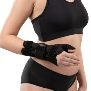 Kobieta w sportowym stroju z opaską na nadgarstek, trzymająca rękę na brzuchu, na jasnym tle.