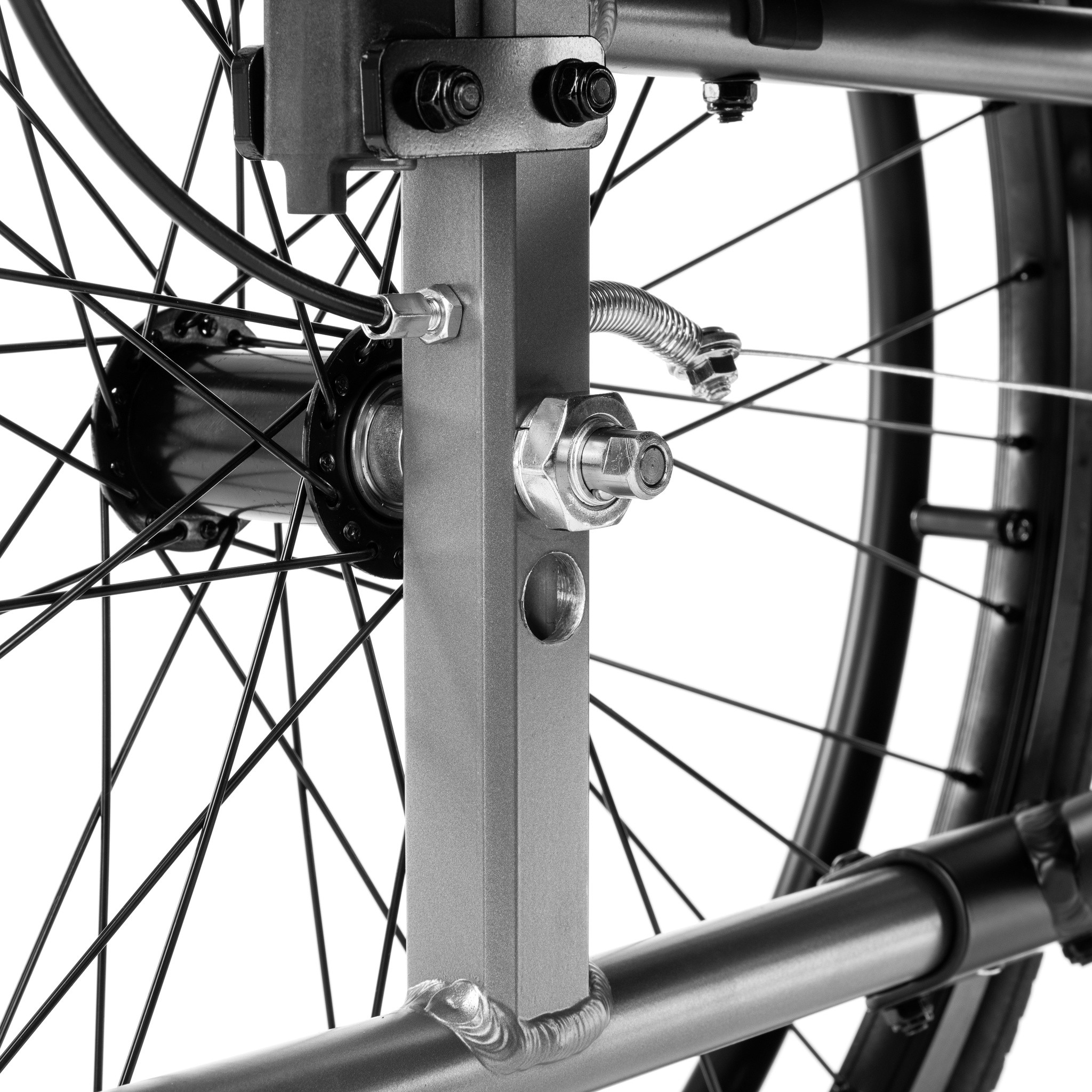 Szczegóły mechanizmu napędu i osi koła wózka inwalidzkiego, z widocznymi metalowymi elementami i szprychami.