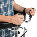 Osoba na wózku inwalidzkim trzyma uchwyty joysticków sterujących.