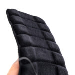 Czarna, puchowa rękawica z wyraźnym pikowaniem, trzymana przez osobę na tle białego.