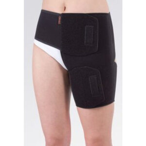 Kobieta nosi czarny stabilizator na biodro i udo z rzepami, zapewniający wsparcie i stabilizację po urazie lub operacji.