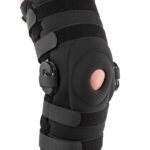 Kolano z protezą wspierającą, z czarną osłoną, regulowanymi paskami i elementami stabilizującymi.