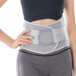 Osoba nosząca biały pas ortopedyczny na talii, ubrana w czarny top i szare legginsy.
