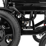 Blisko widoczny czarny wózek inwalidzki z dużym kołem i metalowymi elementami konstrukcyjnymi.
