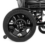 Koło wózka inwalidzkiego z czarną, gładką felgą i oponą z osłoną tekstylną.