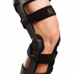 Orteza kolana z czarnym stelażem i pasami mocującymi na udzie i łydce.
