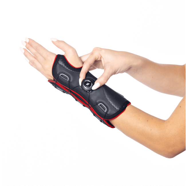 Osoba zakłada na rękę elektroniczny stymulator mięśni z regulatorem i przewodzącymi elektrodami.