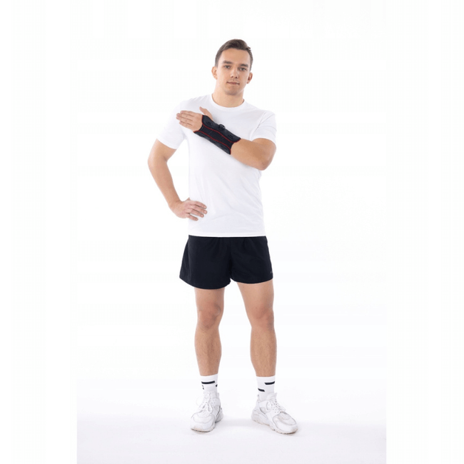 Mężczyzna w sportowym stroju, trzymający rękę na ramieniu, na białym tle, w sportowych butach i skarpetach.