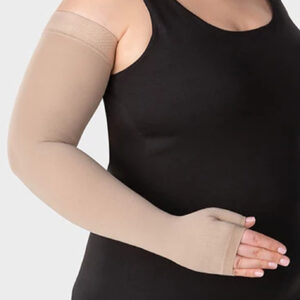 Osoba w czarnym topie i bezuciskowych, beżowych ortezach na rękach, trzymająca się brzucha.
