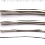 Zestaw czterech metalowych narzędzi chirurgicznych o różnej długości i kształcie, ułożonych poziomo na białym tle.