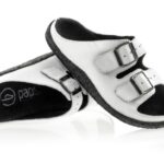 Białe sandały z czarnymi wyściółkami i dwoma regulowanymi paskami na klamry.