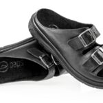 Czarne kapcie z dwoma regulowanymi paskami na rzepy, miękką wyściółką i antypoślizgową podeszwą.