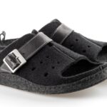 Czarne kapcie z szerokim paskiem z metalową klamrą i otwartym palcem, na miękkiej podeszwie.