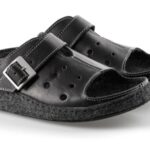 Czarne kapcie z szerokim paskiem i metalową klamrą, wykonane z miękkiego materiału, na podeszwie z filcu.