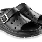 Czarne sandały z zapięciem na sprzączkę i otwartym palcem, wykonane ze skóry, na płaskiej podeszwie.