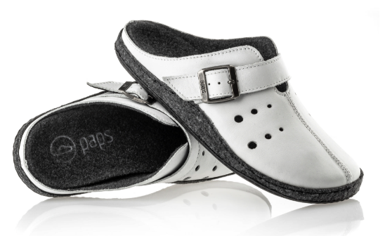 Białe kapcie z czarną podeszwą, zapinane na regulowany pasek z klamrą, przeznaczone do użytku domowego.