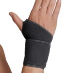 Dłoń z czarnym stabilizatorem nadgarstka na nadgarstku, skierowana do góry.