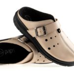 Beżowe pantofle z czarną podeszwą i regulowanym paskiem na rzep, przeznaczone do użytku domowego lub na co dzień.