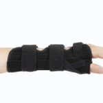 Orteza na rękę z czarnymi pasami i zapięciami, zakładana na przedramię.