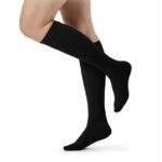 Para czarnych podkolanówek na nogach osoby stojącej na palcach.