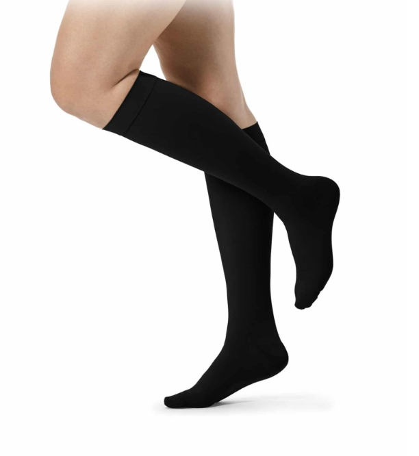 Para czarnych podkolanówek na nogach osoby stojącej na palcach.